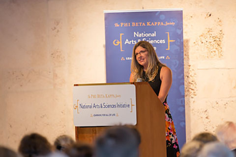 A woman delivering a speech for an event in the arts and sciences field